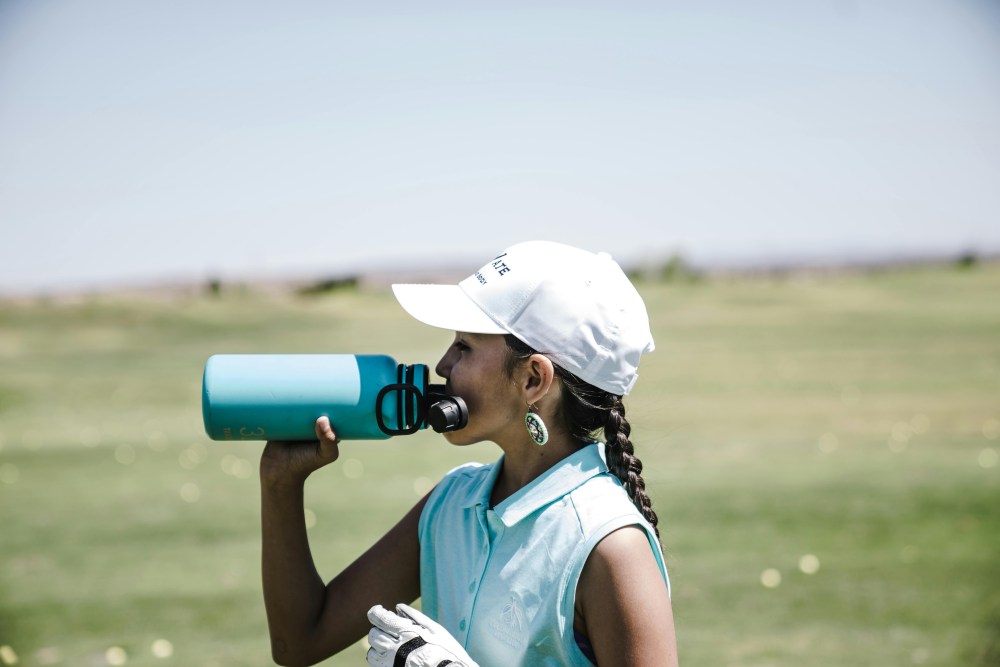 A woman drinks water from a water bottle.