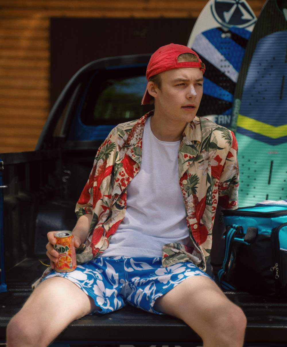 A man wearing a Hawaiian shirt and a baseball cap backwards.