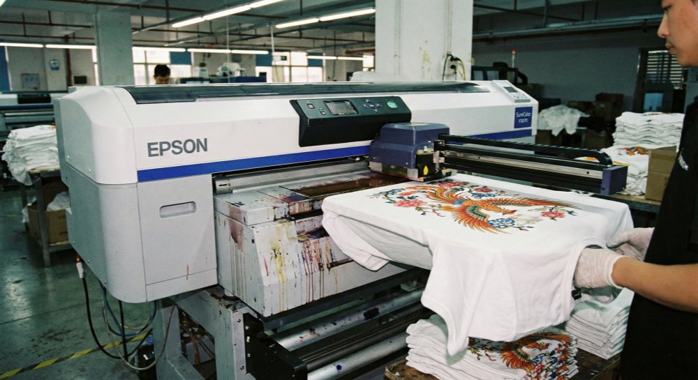 The factory's printer is printing T-shirts.