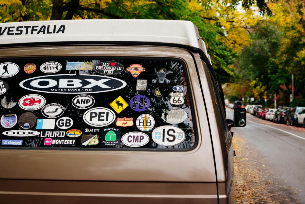 A car's rear windshield was covered with various bumper stickers.